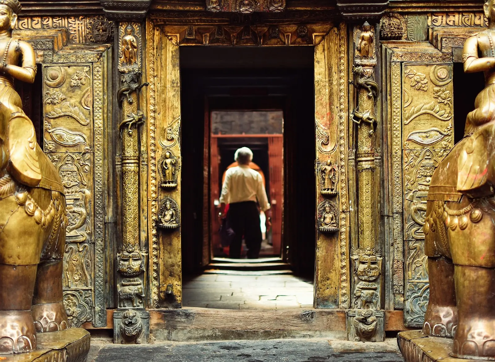 A person walking through Hiranya Varna Mahavihar, a Newar Buddhist temple in Nepal.