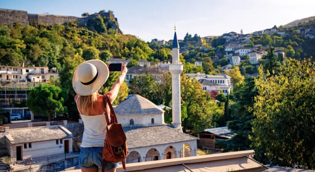 Woman tourist taking picture with smartphone of beautiful mosque in Gjirokaster city Albania