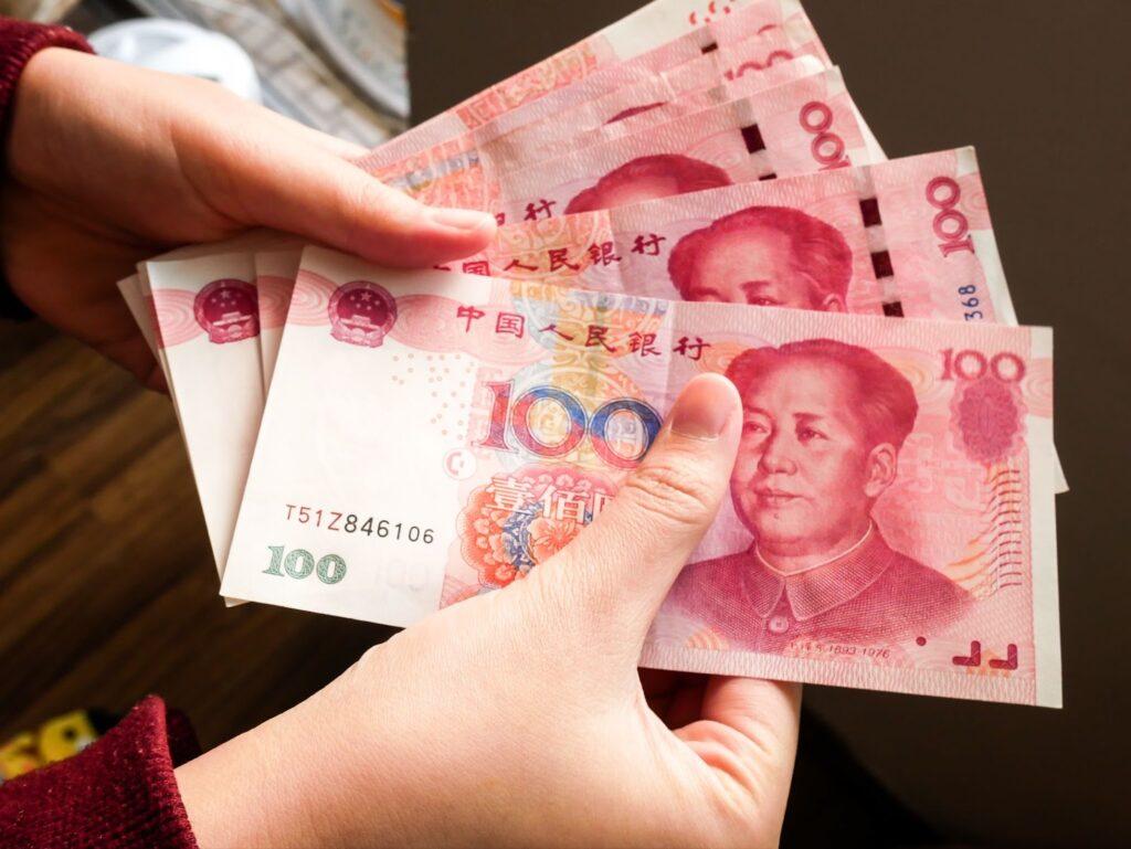 A pile of 100 RMB banknotes of Chinese yuan money in a female hand exchanging for travel.