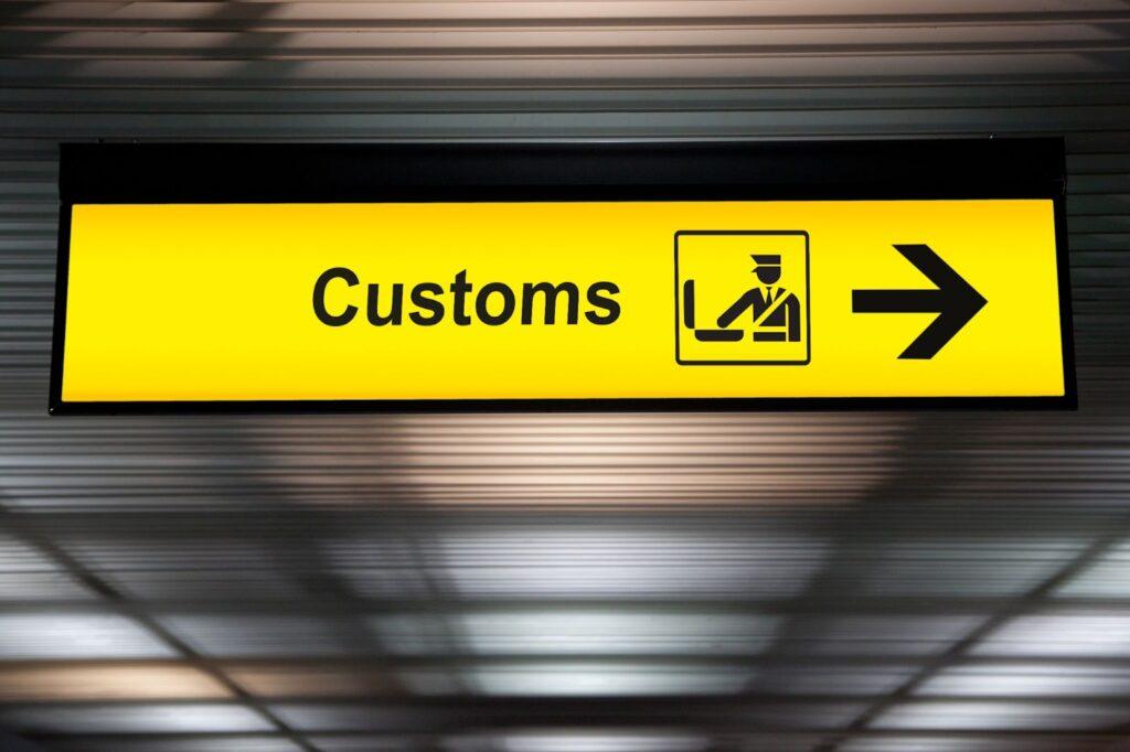 airport customs declare sign with icon and arrow hanging from airport ceiling at international terminal.