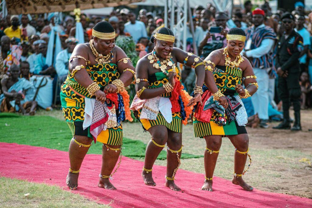 Three women in a colorful traditional dress dancing during the Hogbetsotso festival in Ghana