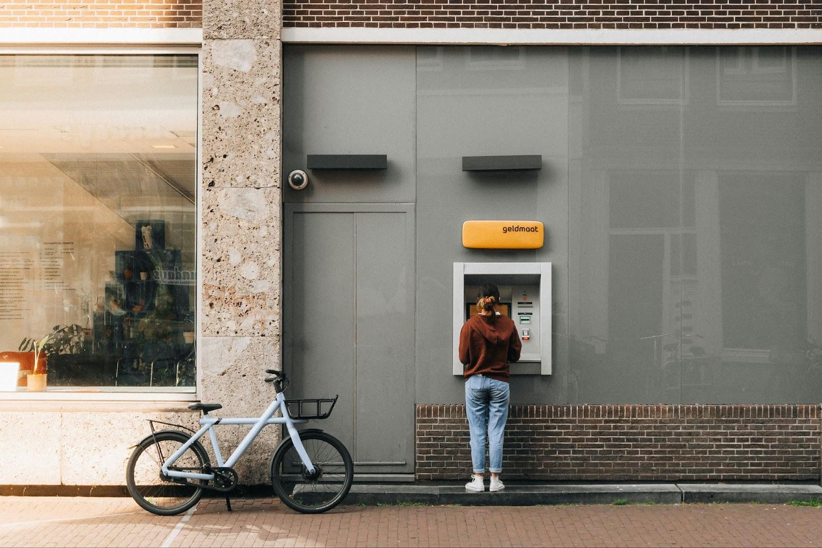 a person standing in front of a atm machine. Amsterdam, Netherlands