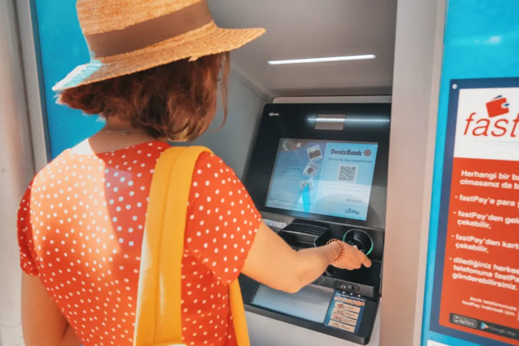 Turkey, Antalya. A female client of Deniz Bank withdraws money from her card account and pays the transaction fee at the ATM machine