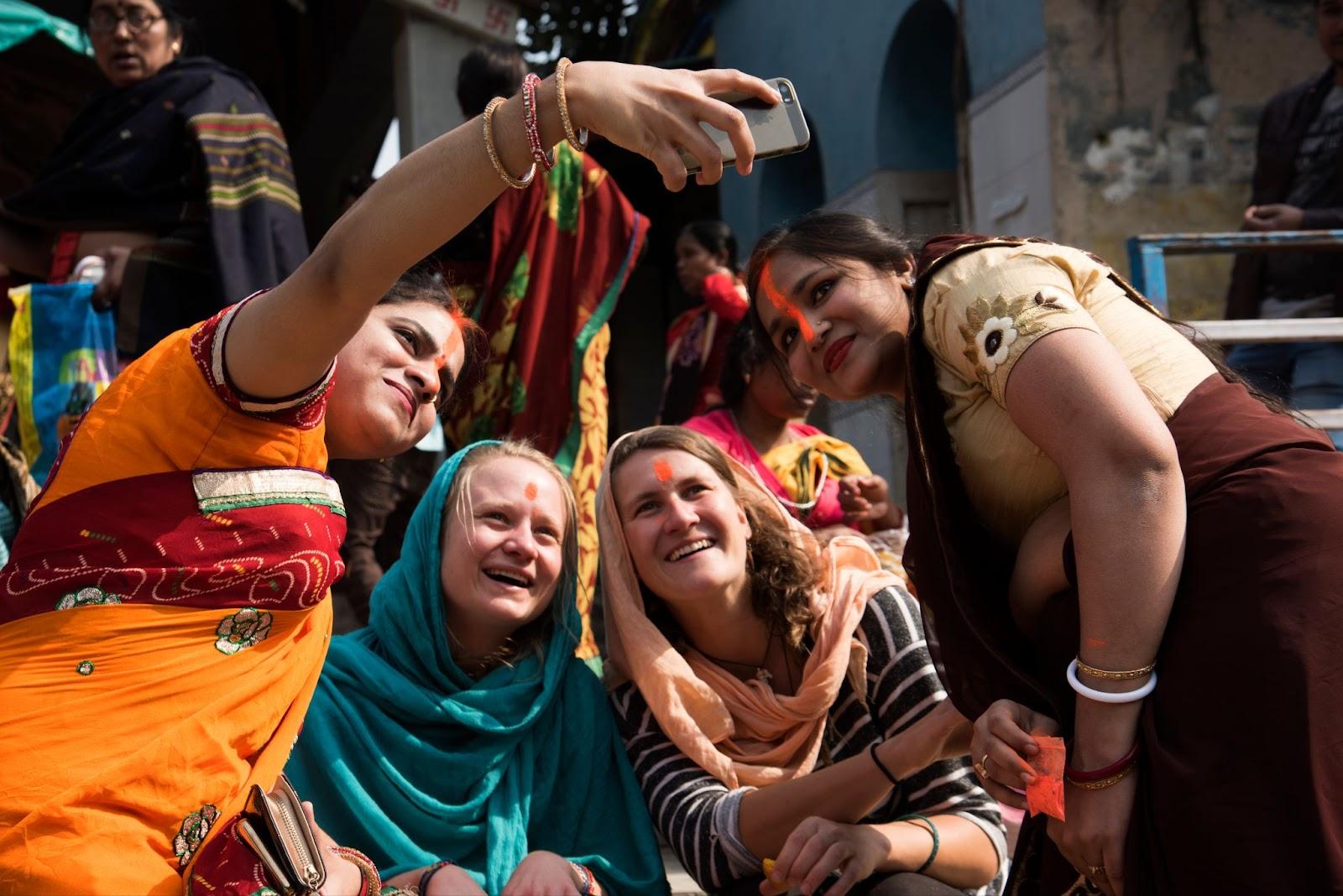 woman taking selfie with foreign tourist at the ghat near the Kali Temple in morning.