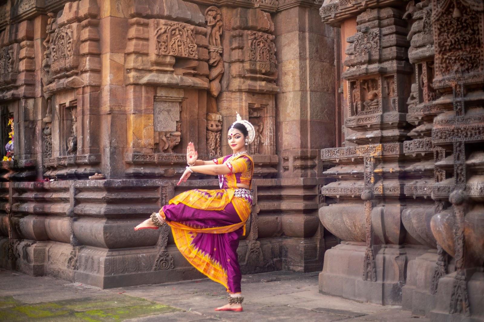 Indian classical odissi dancer at Brahmesvara Temple with sculptures in bhubaneswar, odisha, India