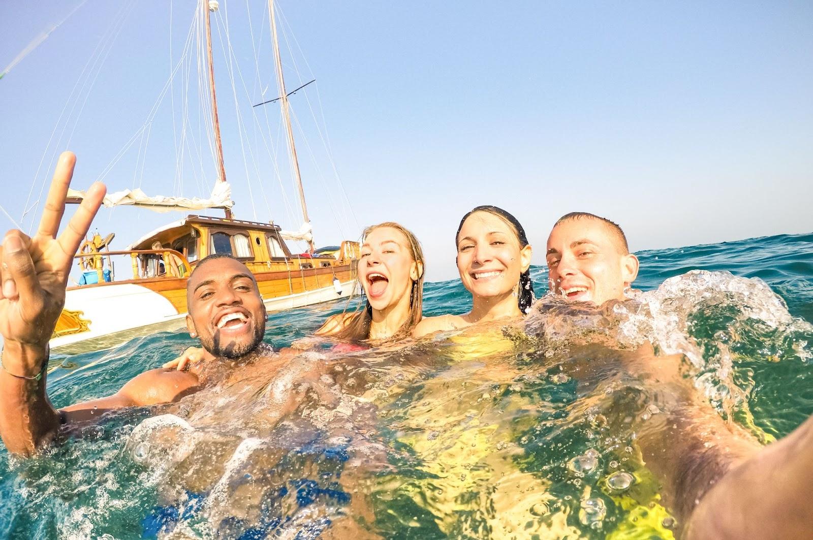 Young multiracial friends taking selfie a few seconds after jumping into the sea