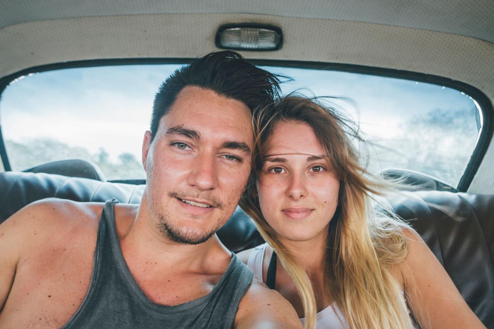 Young couple taking a selfie in a vintage car in Cuba