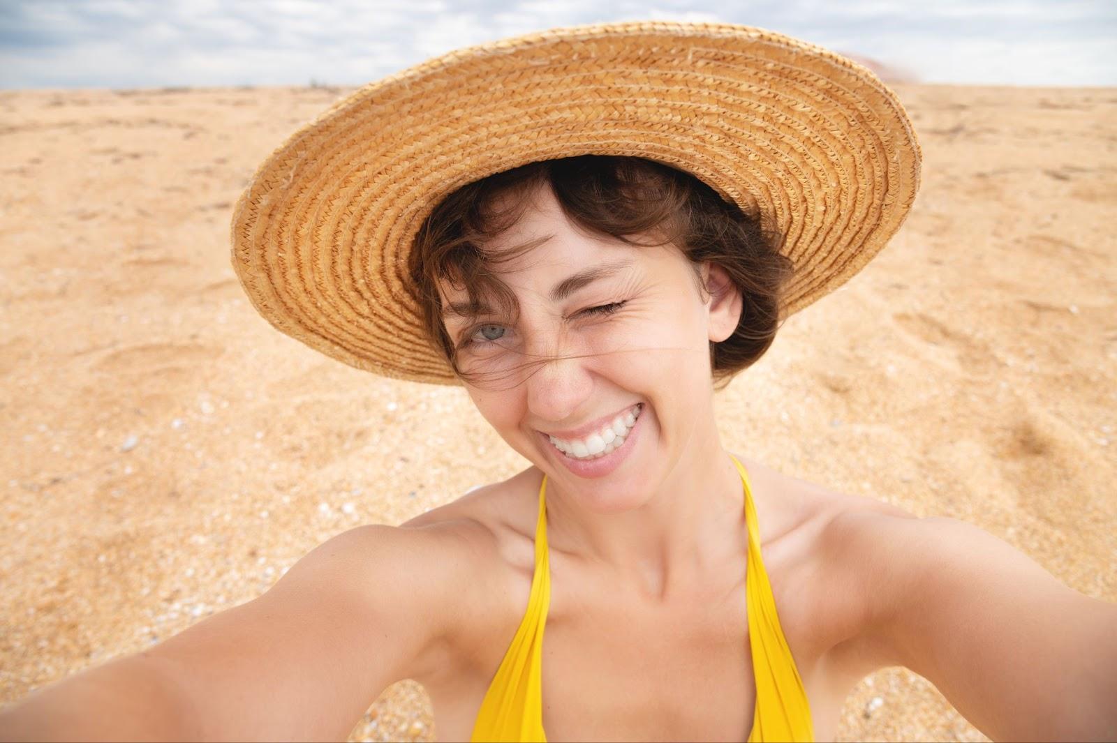 Happy girl taking selfie during summer beach vacation smiling