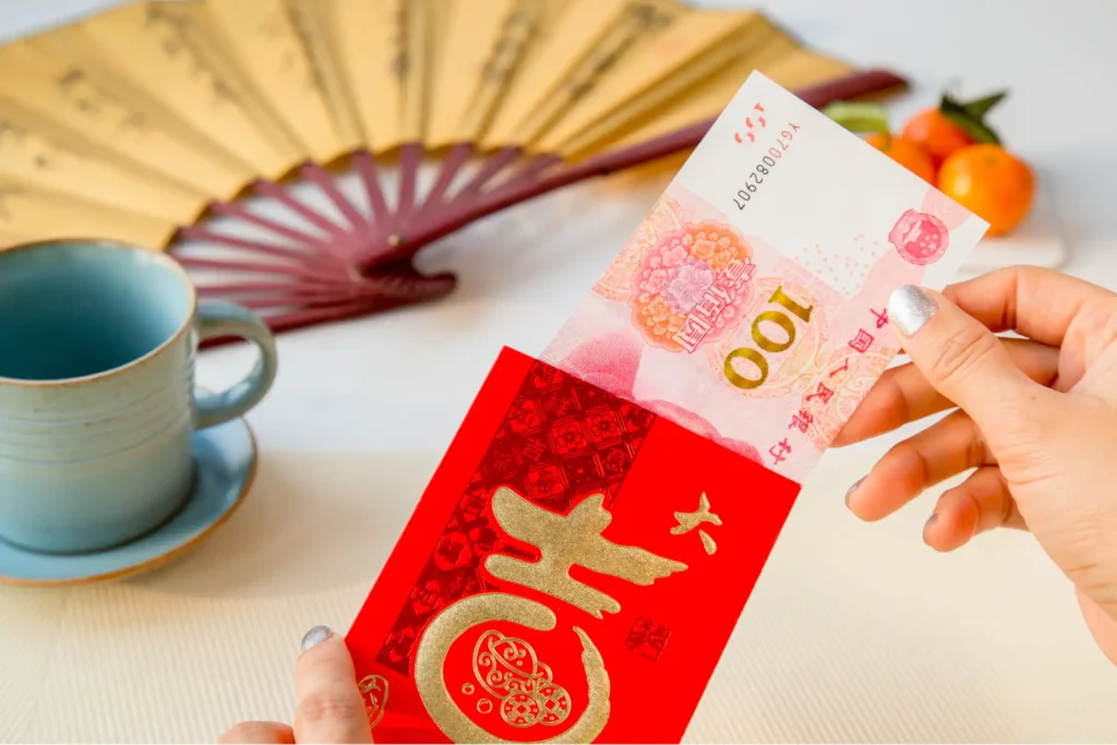 Woman's hand taking out one hundred Yuan from a red envelope with the chinese characters for a lot of luck and fortune