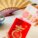 Woman's hand taking out one hundred Yuan from a red envelope with the chinese characters for a lot of luck and fortune