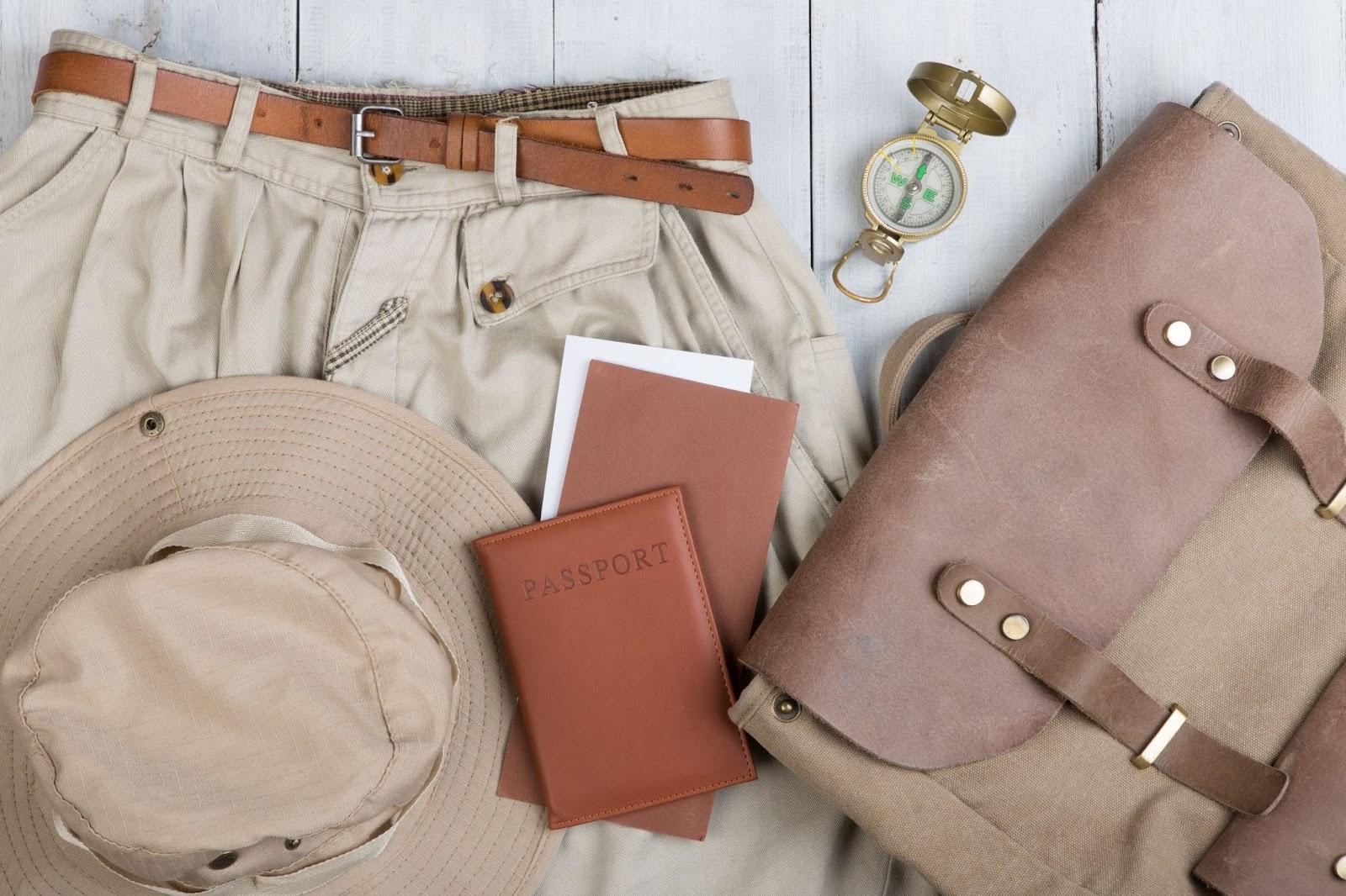 Prepare for journey in safari style, hiking and backpacker - accessories and travel items, packing clothes in backpack: backpack, passport, tickets, hat, shorts, compass on white wooden background