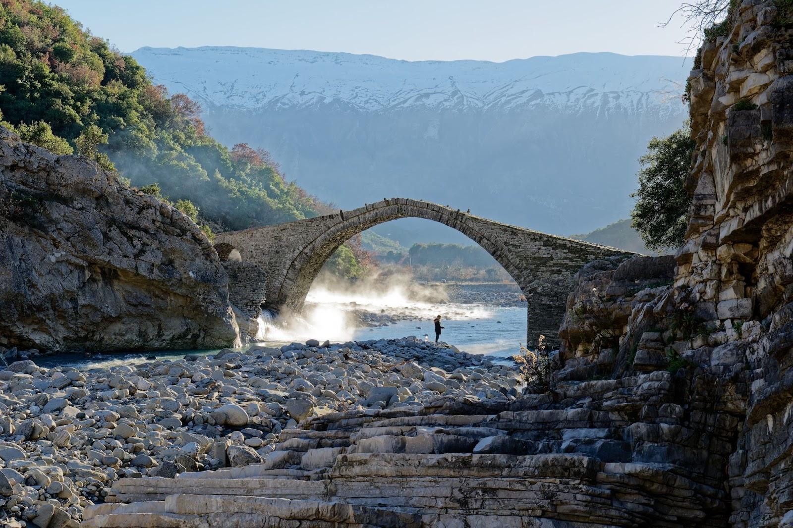 View of the Kadiut Bridge in Benje, Permet, Albania. Ancient stone bridge. Beautiful natural wonders. Holidays and leisure time. Fisherman fishing in the river. Natural thermal baths.