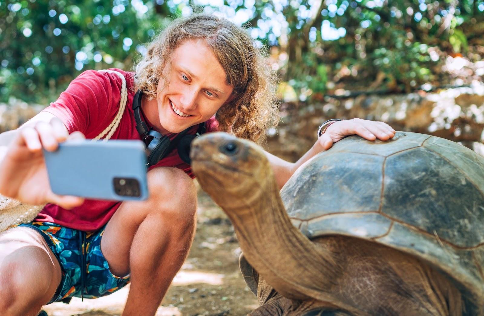 Tourist taking selfie with a turtle
