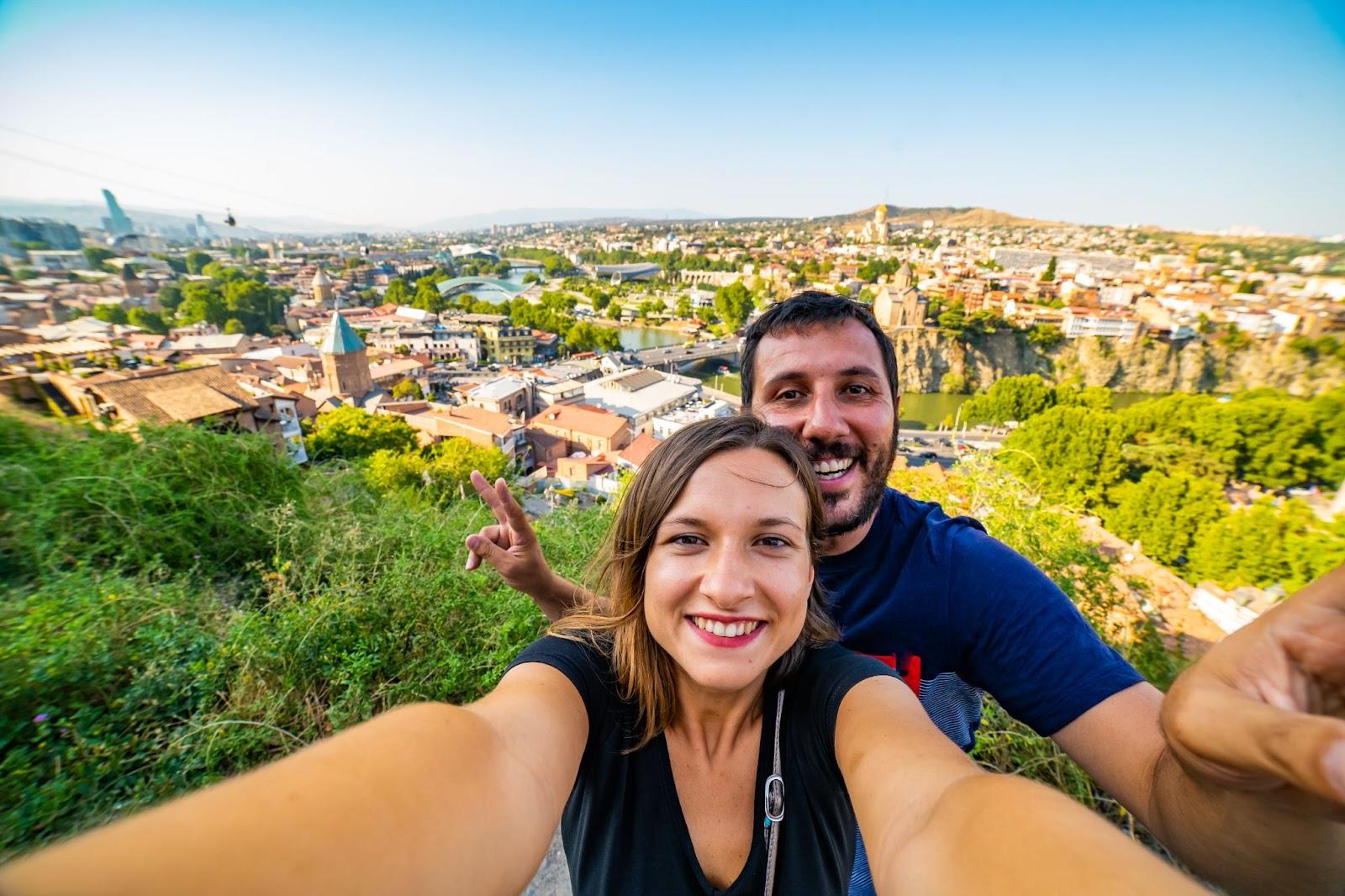 Couple taking selfie in Tbilisi with aerial view of old Tbilisi