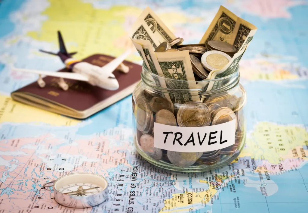 Travel budget concept. Travel money savings in a glass jar with compass, passport and aircraft toy on world map