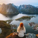 Woman hiking in Lofoten islands travel lifestyle in Norway, girl enjoying aerial view from Reinebringen mountain top active vacations famous spot destinations solo traveler outdoor adventure journey