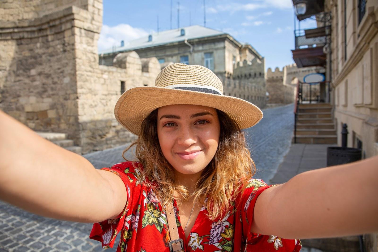 Happy tourist girl taking a selfie in old town street, Baku. She took note of the mid market rate and gt rate alerts from Manor FX 