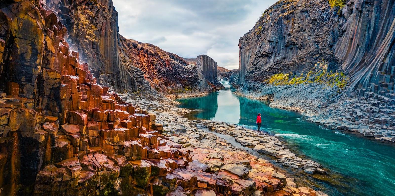 Tourist went to the bottom of canyon and admired the beauty of basalt columns. View from flying drone of Studlagil Canyon. Picturesque summer scene of Iceland. Beauty of nature concept background.