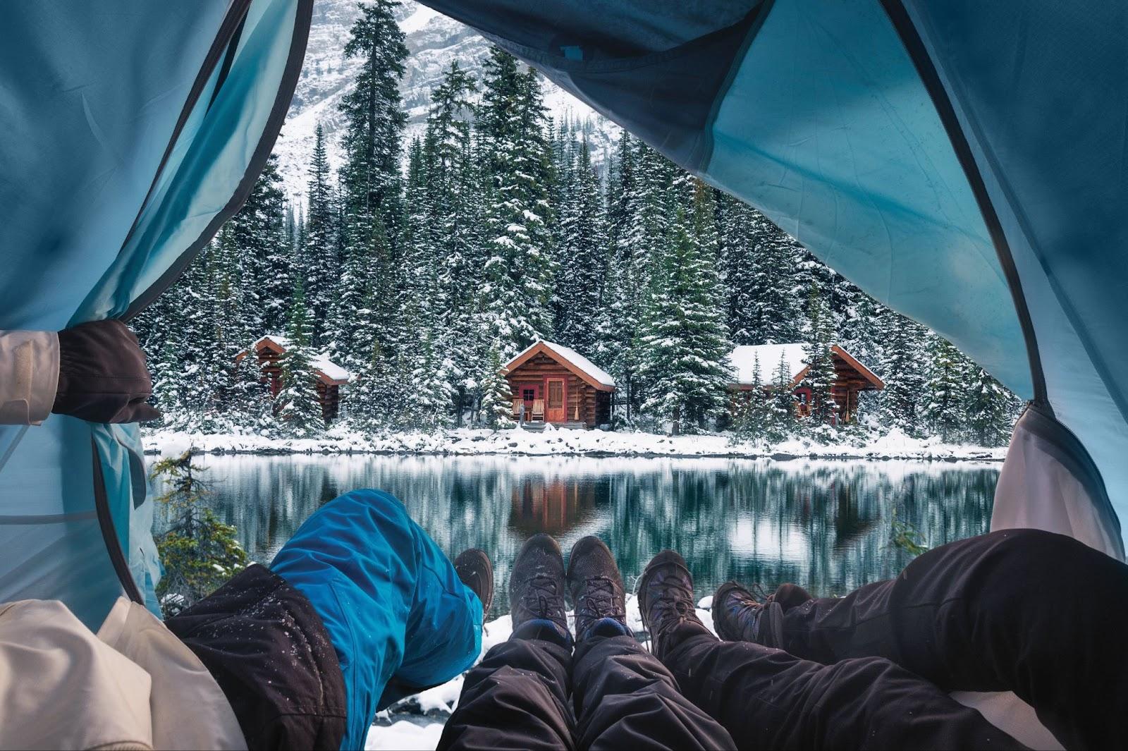 Group of traveler opening tent with wooden lodge in snow forest on Lake O'hara at Yoho national park, Canada