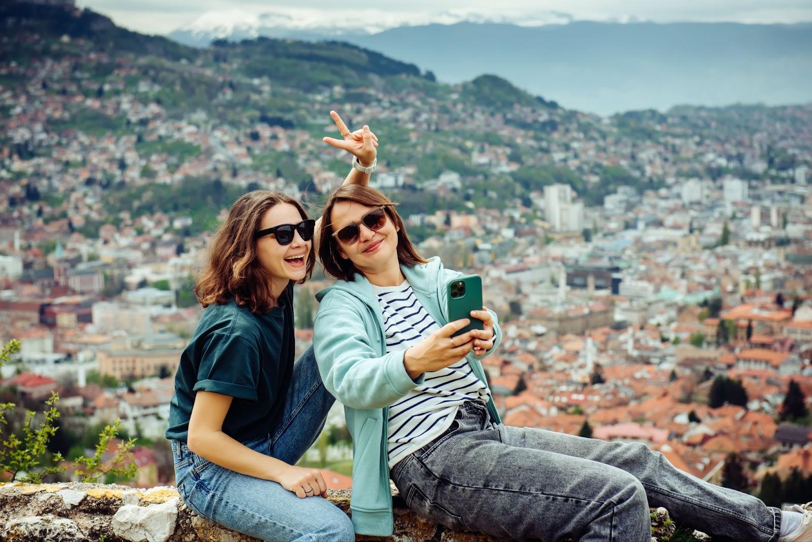 Two female travellers taking a selfie with Sarajevo in the background