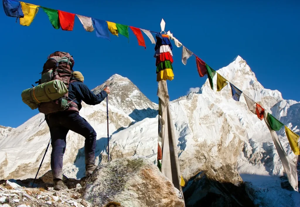 View of Everest with hiker or tourist and buddhist prayer flags from Kala Patthar and blue sky, way to Everest Base Camp, Nepal Himalayas mountains